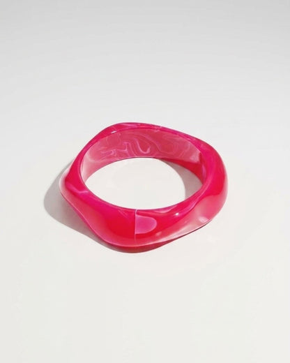 A glossy, vibrant pink acrylic bangle with an irregular, organic shape.
