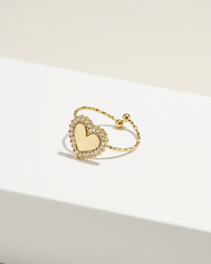 Gold adjustable ring with a pavé-set crystal heart on a white surface.