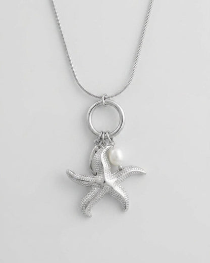 Silver-tone pendant necklace with a textured starfish charm and a white pearl bead on a round bail and snake chain.