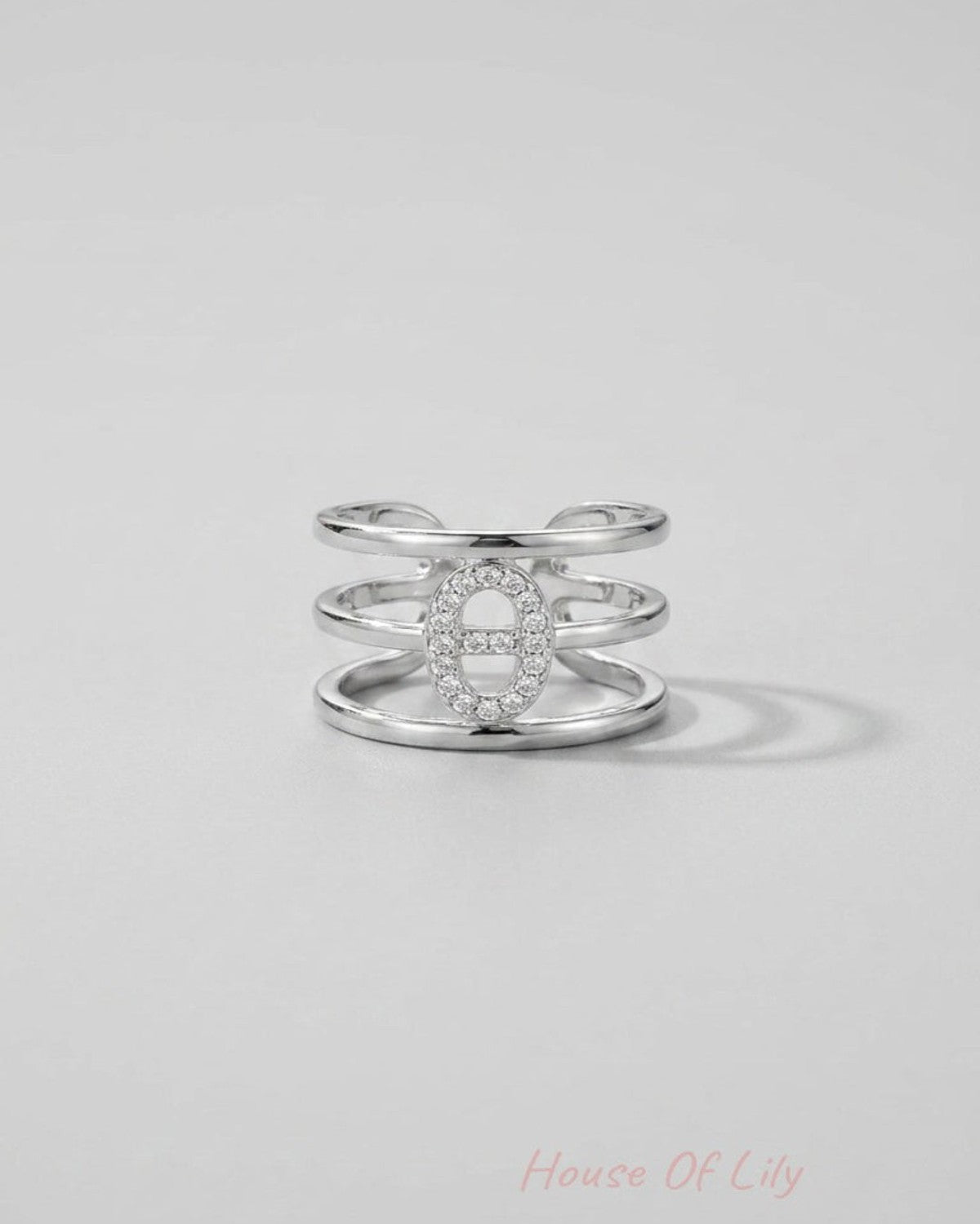 Silver tiered statement ring featuring three parallel bands connected by an elliptical pavé-set crystal centerpiece.