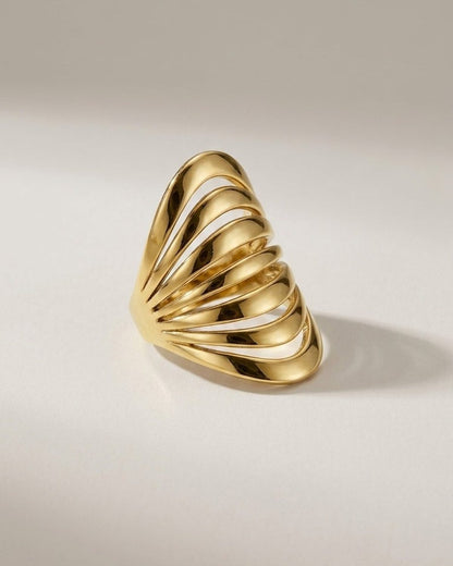 Polished gold multi-band ring with a tiered, architectural design on a light background.