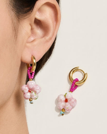 Gold hoop earrings featuring a pink beaded loop and a speckled pink ceramic flower pendant.