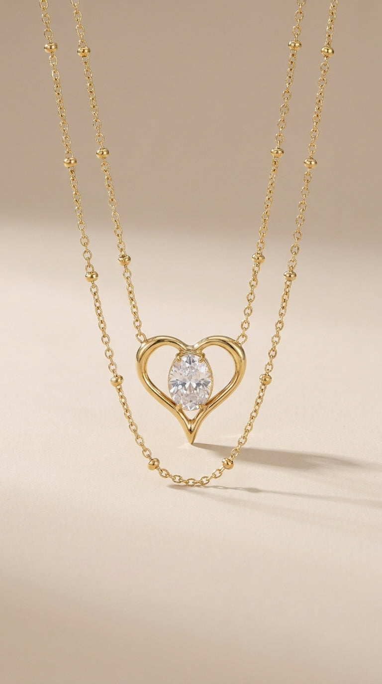 Gold-finish stainless steel layered necklace featuring a heart-shaped pendant with a central oval stone.
