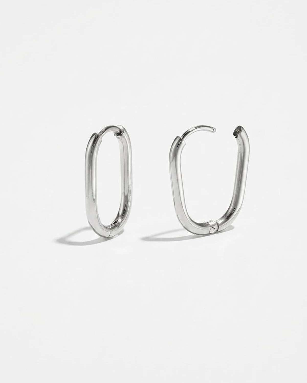 House of Lily silver oval hoop earrings with a polished finish and minimalist hinged design on a white background.