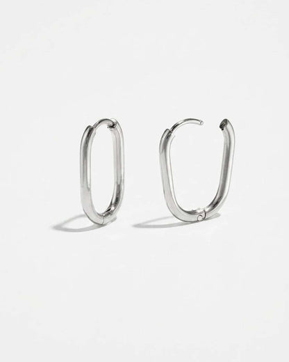 House of Lily silver oval hoop earrings with a polished finish and minimalist hinged design on a white background.