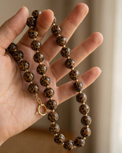 Round leopard print beads on a gold-tone clasp necklace.