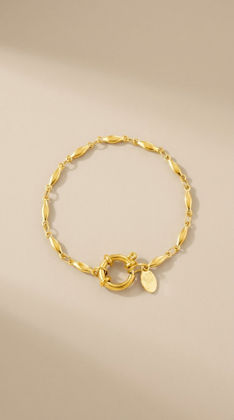 Gold oval chain bracelet with a large round clasp and small logo charm.