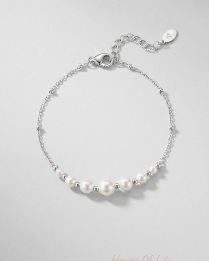 Silver chain bracelet with a graduated row of white pearls separated by small silver beads.