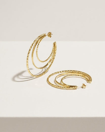 Stacked Aura Gold hoop earrings feature three concentric gold-plated loops with textured and smooth finishes.