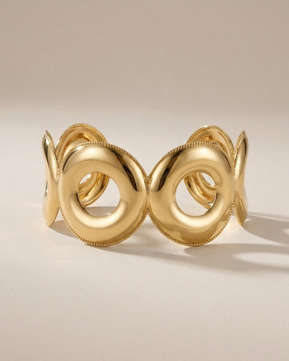 Gold Geometric Cuff bracelet featuring interlocking polished circular rings with beaded trim on a neutral background.