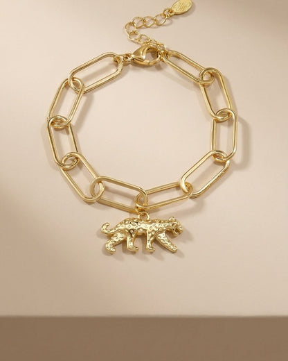 Gold link chain bracelet featuring a textured leopard charm with spots, on a beige background.