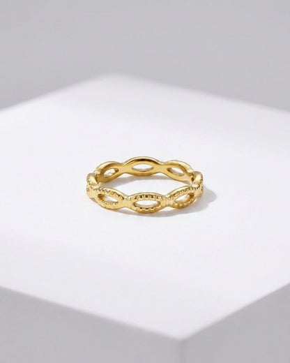 Gold band ring with an openwork braided or looped link design, centered on a white display surface.