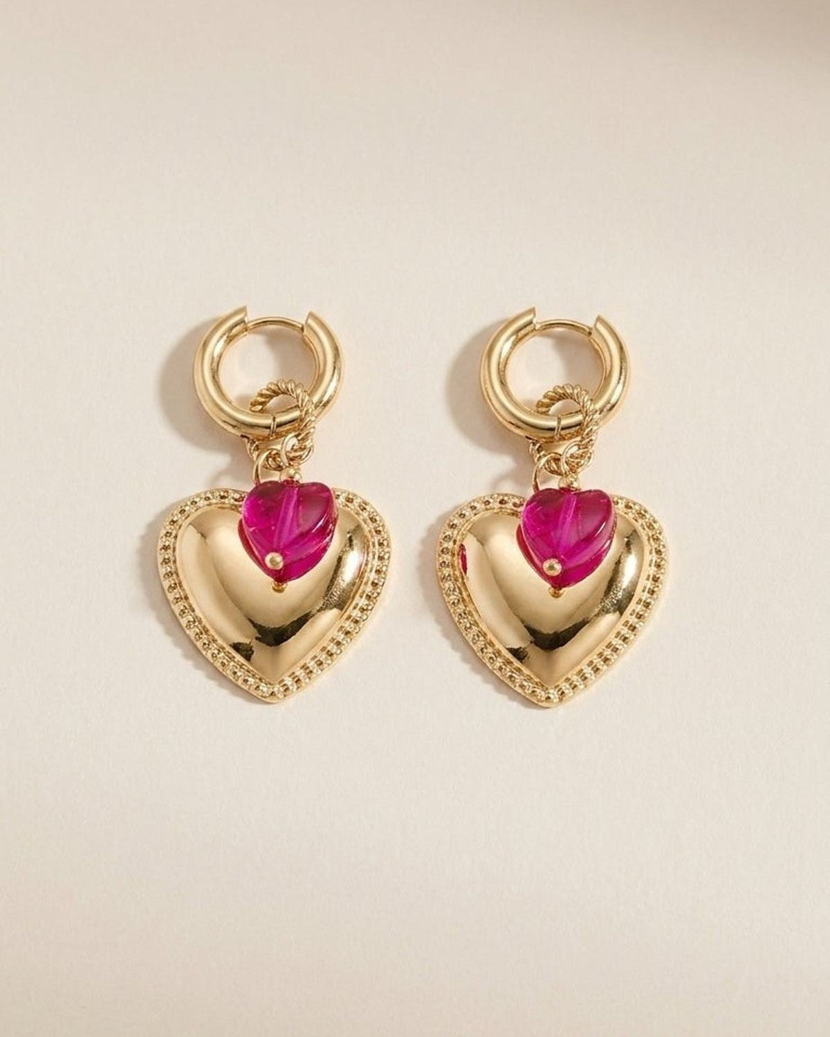 Gold hoop earrings with beaded trim hearts and smaller pink crystal hearts suspended below.