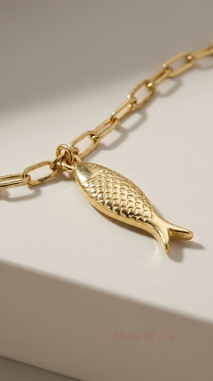 Gold chain bracelet featuring a textured, polished fish charm with fine scale details.
