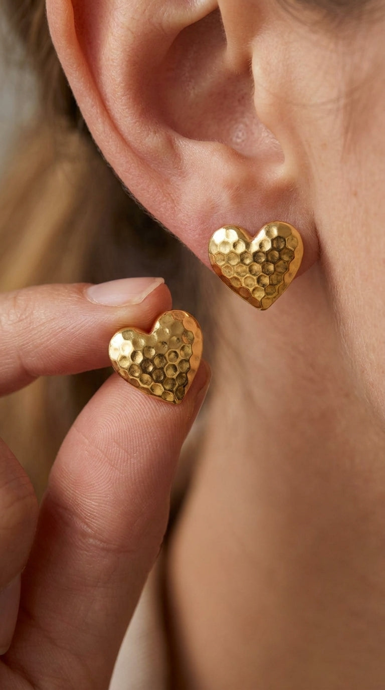 Gold-tone stud earrings in a heart shape with a textured, hammered honeycomb surface.