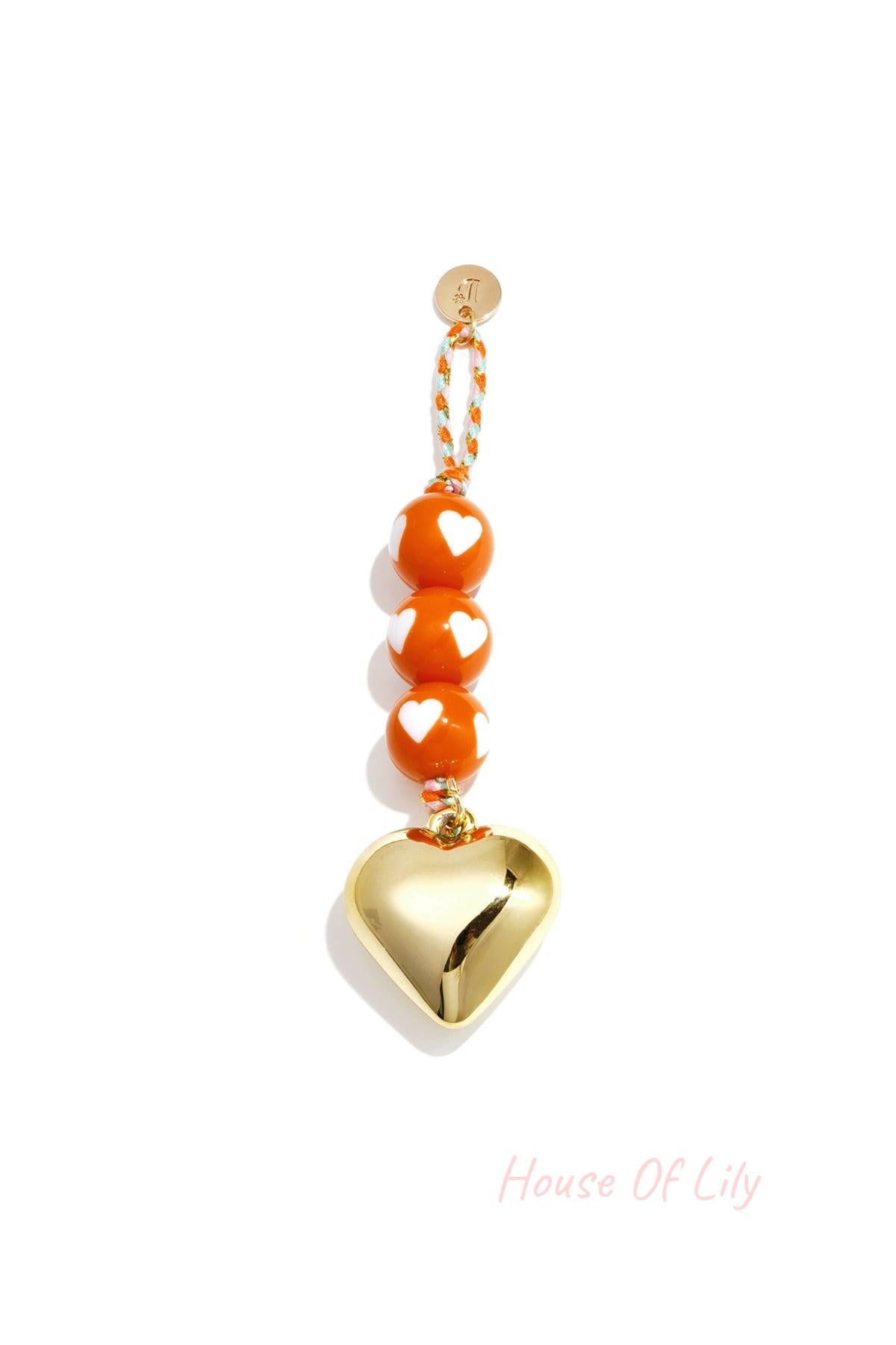 Orange heart charm bag keychain with gold heart pendant and heart-patterned beads on braided cord