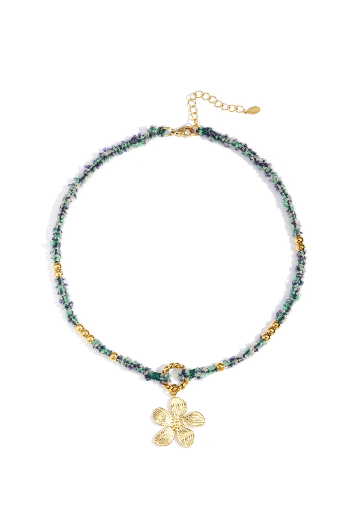 Close-up of a chic floral charm necklace with green and blue woven rope, gold beads, and a gold flower pendant on a white background