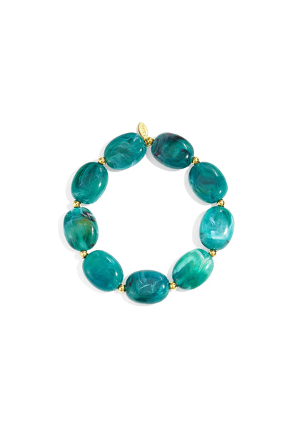 Close-up of a teal green acrylic beaded bracelet with gold spacers on a white background