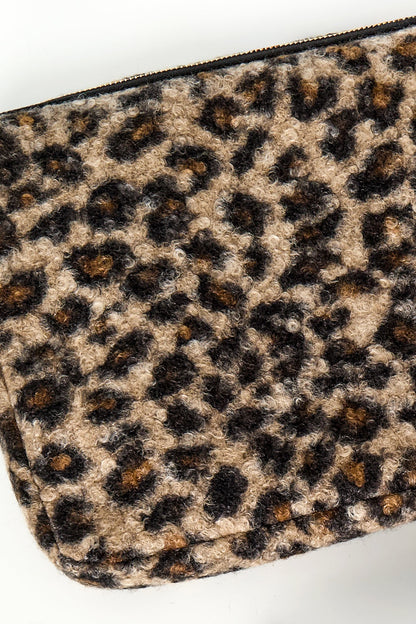 Close-up detail of textured boucle leopard print fabric in warm brown and black tones