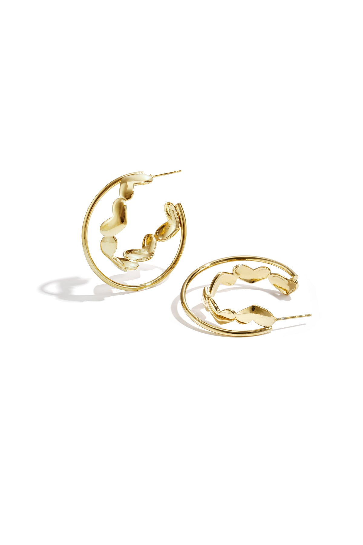 Gold hoop earrings with heart-shaped accents laid on white background