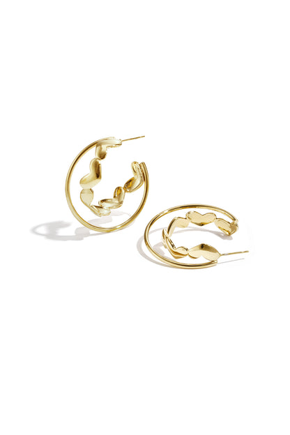 Gold hoop earrings with heart-shaped accents laid on white background