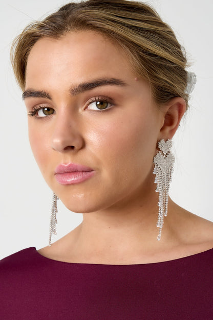 Close-up of model wearing silver-tone crystal cascade earrings styled with burgundy top and neutral makeup