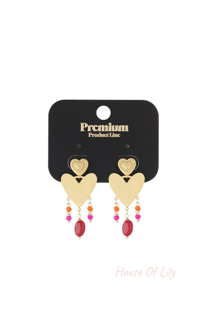Gold-tone heart drop earrings with dangling colorful beads in pink, orange, and red on a branded black display card.