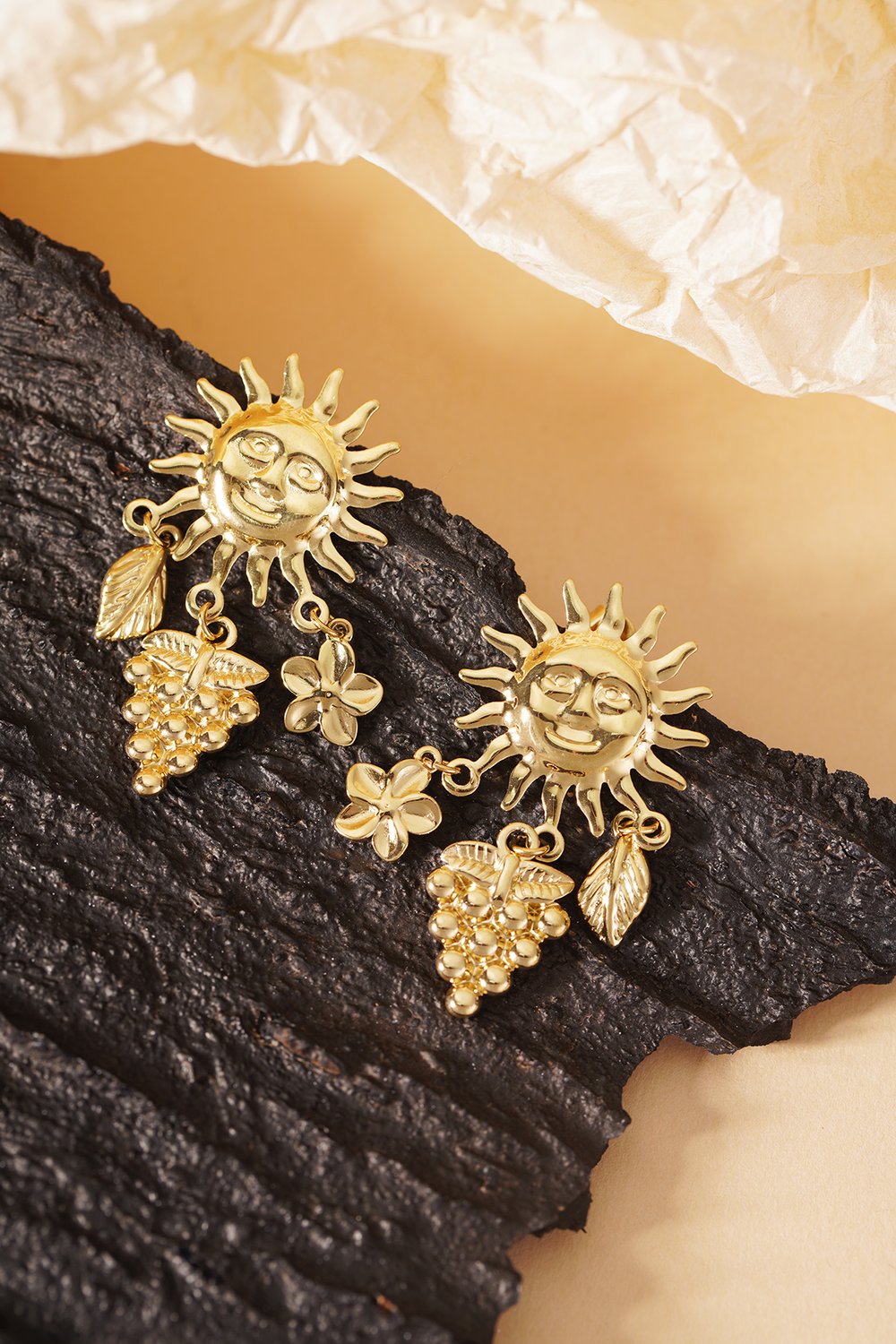 Golden Hour Drops: Gold-tone earrings featuring a smiling sun motif with dangling grape, leaf, and flower charms.