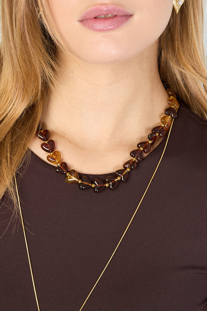 Brown and amber gradient heart bead necklace with gold spacers on white background