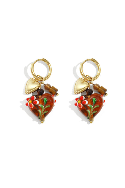 Pair of gold hoop earrings with brown glass heart charms decorated with red and white flowers and gold heart pendants