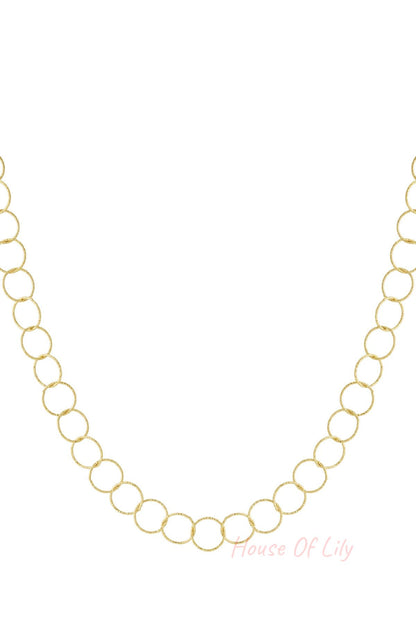 Close-up of textured loop chain necklace in gold tone on white background