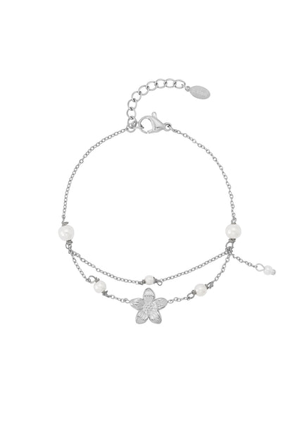 Silver double layer charm bracelet with flower pendant and faux pearls on a white background