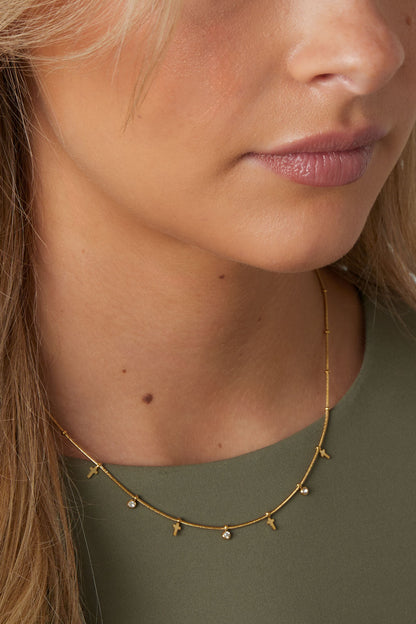 Close-up of woman wearing the delicate gold cross necklace with rhinestones