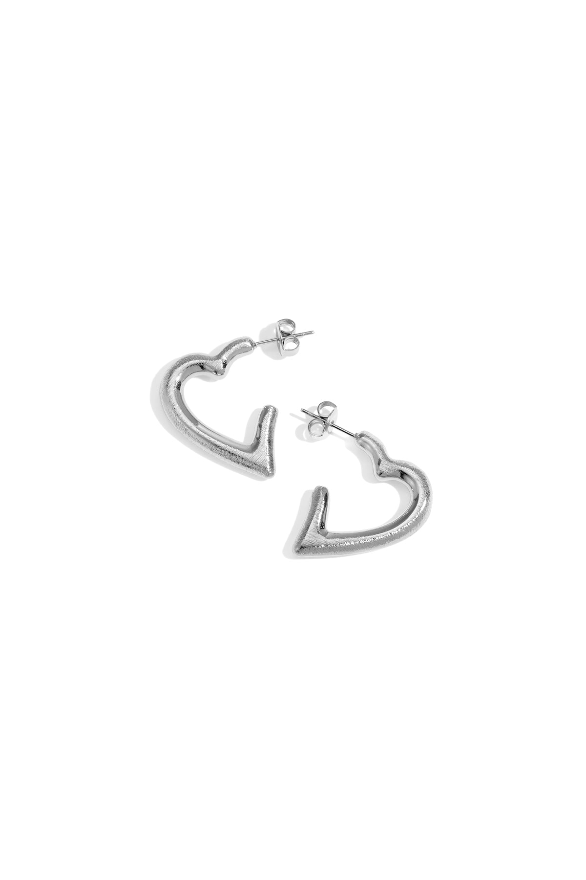 Pair of sculpted heart-shaped silver hoop earrings on white background