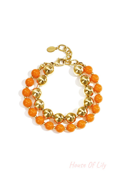 Double layered bracelet with orange acrylic and gold-tone beads on white background