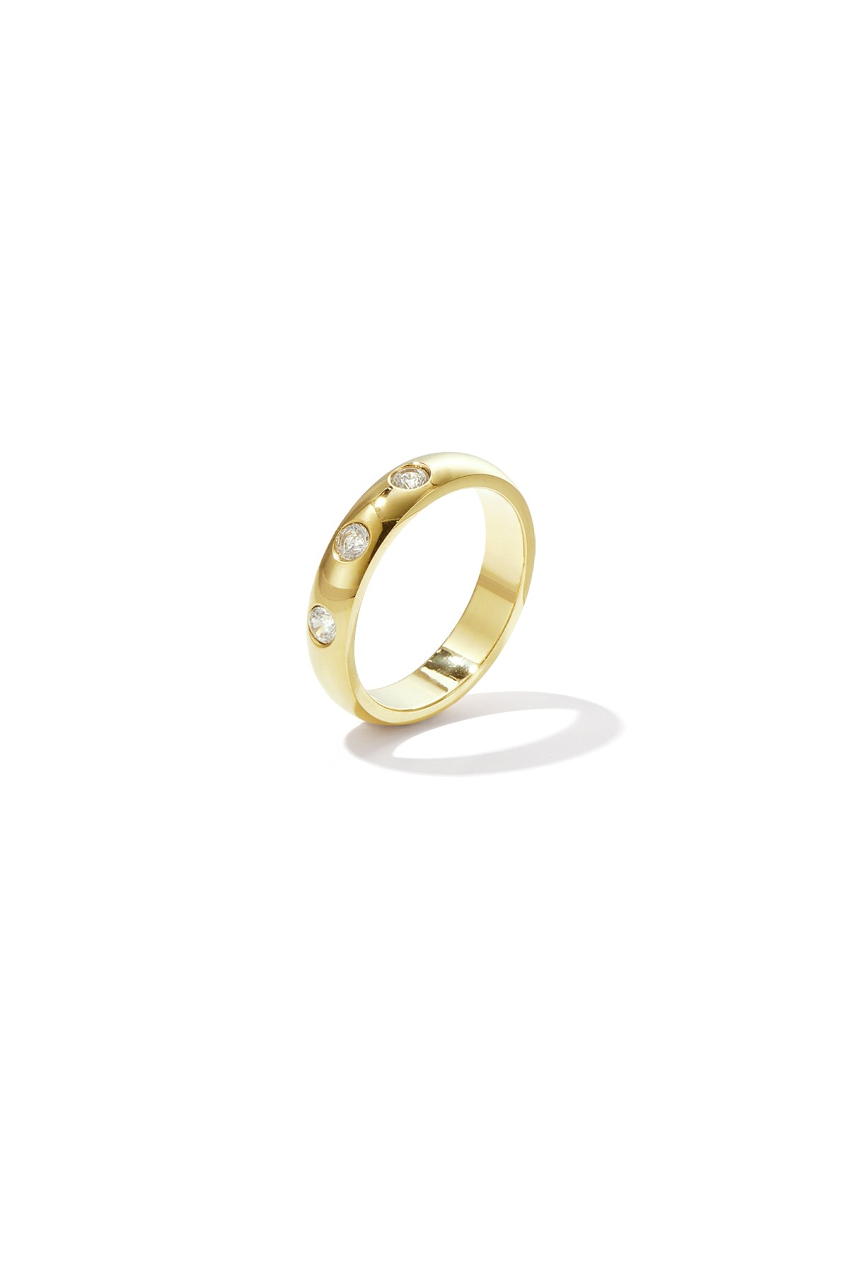 Close-up image of a gold ring adorned with three clear stones embedded in the band on a white background