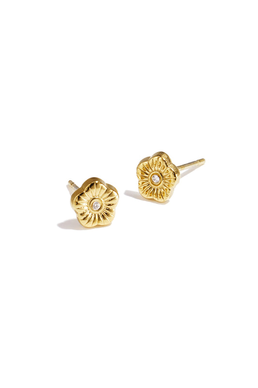 Close-up photo of gold floral mini stud earrings with rhinestone center on white background