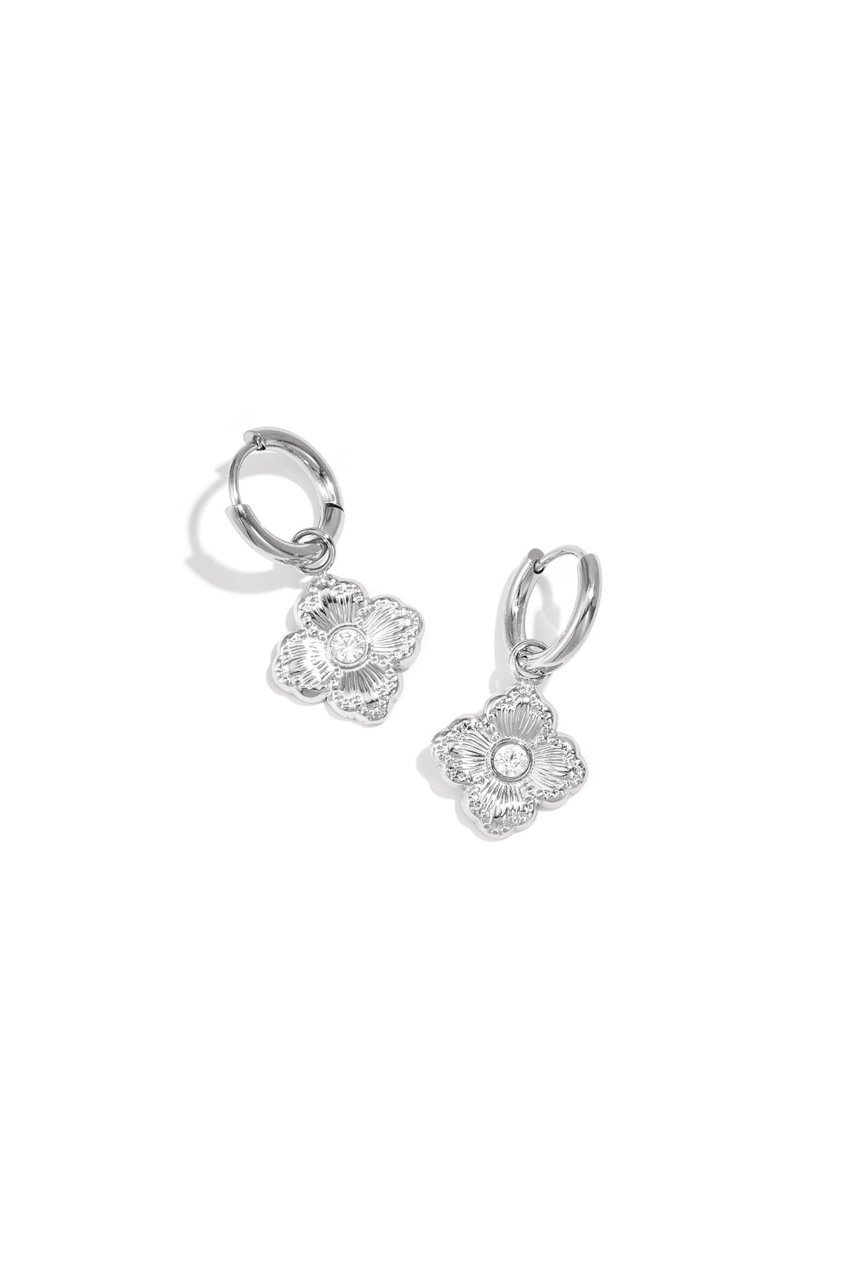 Pair of silver-tone clover charm drop earrings with zircon stones on white background