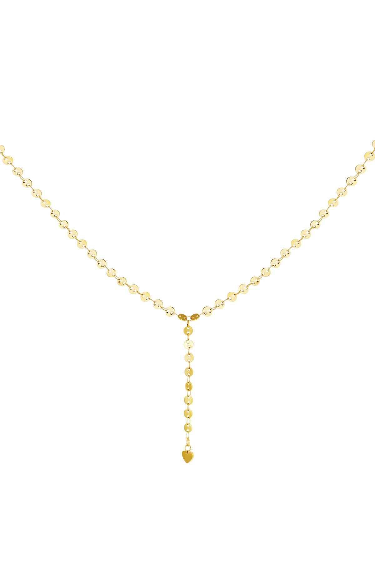 Close-up of a delicate gold Y-chain necklace with small circular chain links ending in a tiny heart charm