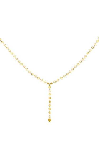 Close-up of a delicate gold Y-chain necklace with small circular chain links ending in a tiny heart charm