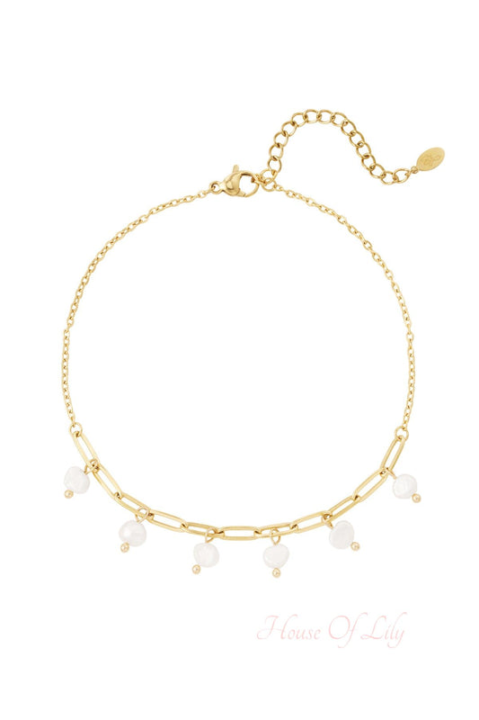Close-up of a gold chain anklet with six white pearl charms and an adjustable clasp on a white background