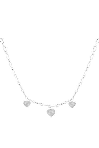 Silver version of triple heart charm necklace displayed on white background