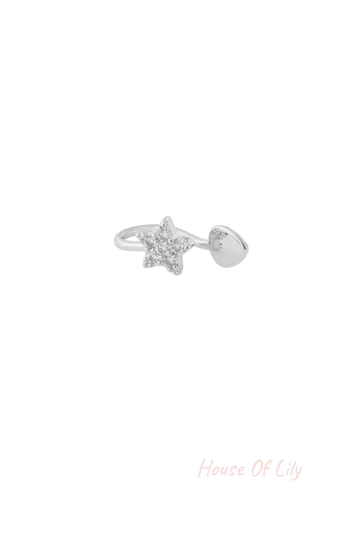 Close-up of silver star-shaped ear and nose cuff with sparkling cubic zirconia stones on a white background