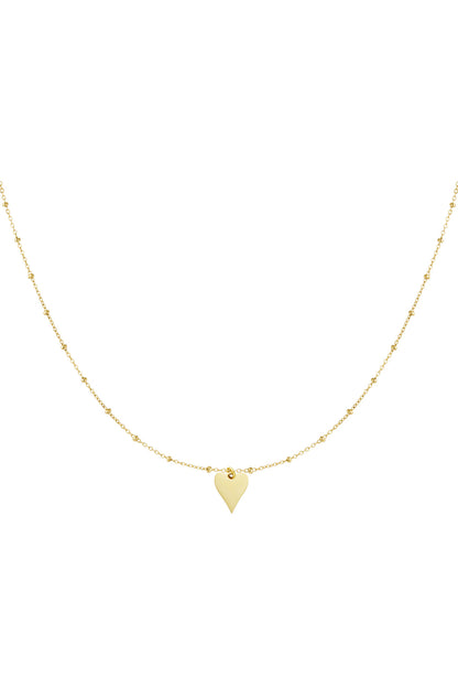 Close-up of delicate gold chain necklace with tiny beads and a small polished heart pendant.