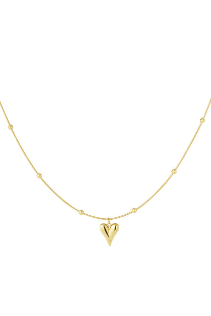 Close-up of a gold heart pendant necklace with evenly spaced small gold balls on a delicate chain