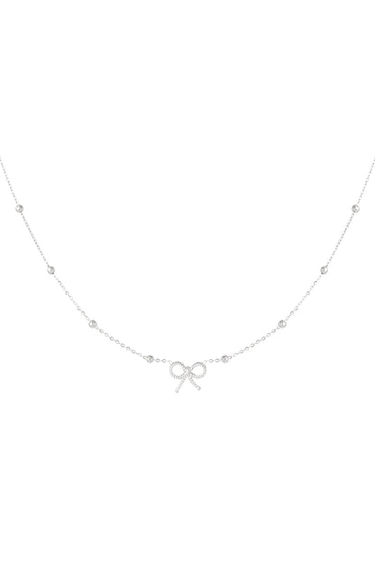 Detailed shot of a delicate silver bow pendant necklace with a fine chain and spaced bead accents