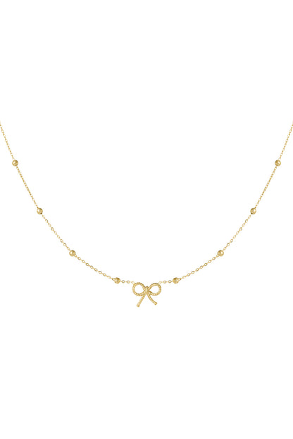 Close-up of a delicate gold bow pendant necklace featuring a fine chain with small evenly spaced beads