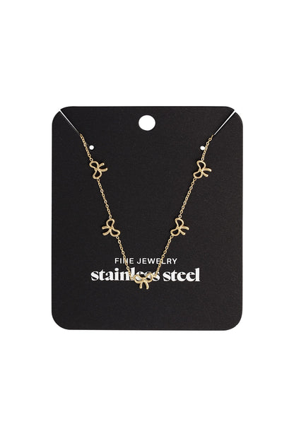 Gold bow charm necklace displayed on a black jewelry card labeled stainless steel fine jewelry