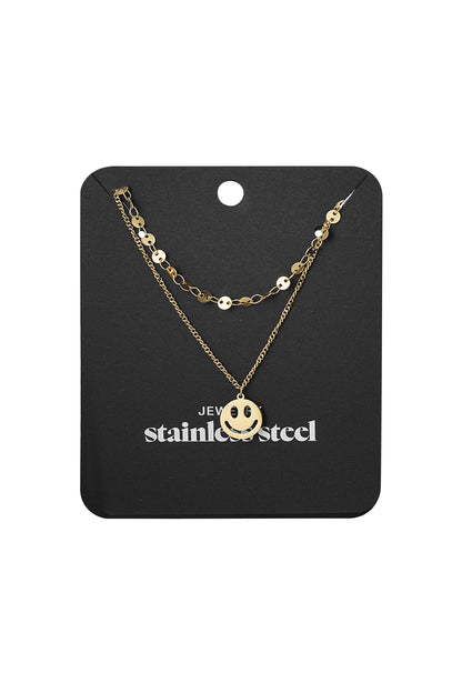 Gold layered smiley face necklace displayed on black jewelry card with stainless steel label