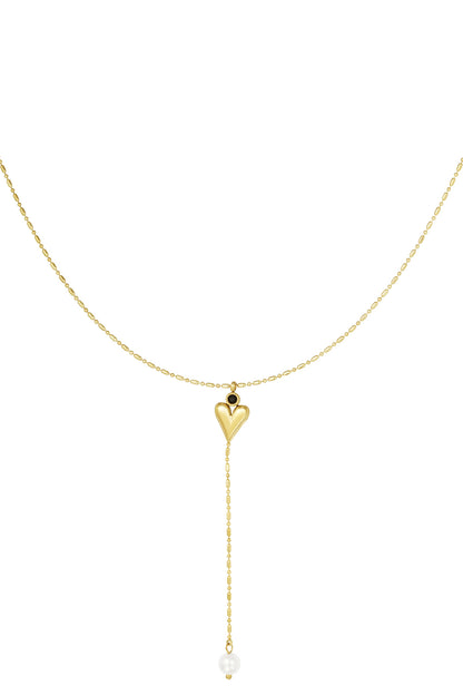 Gold-tone necklace with heart pendant featuring black gemstone and dangling chain ending in white pearl on white background